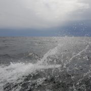 Foto av bølgesprut, hav og himmel.